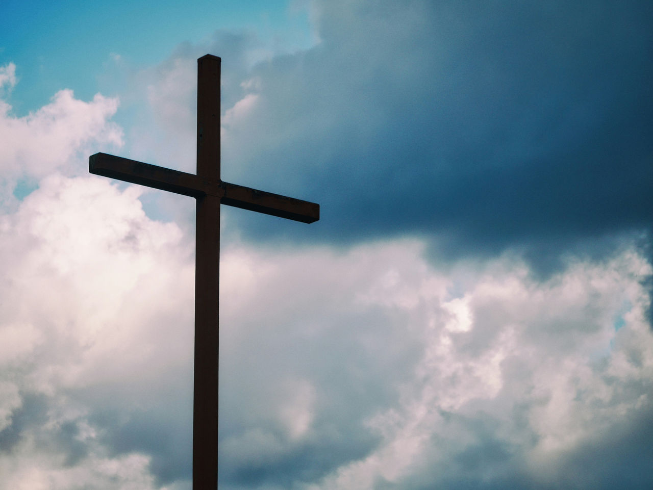 Black cross under blue sky background